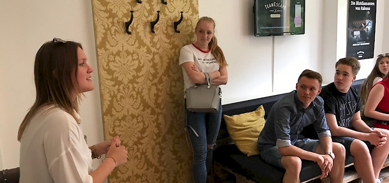 Eine Mitarbeiterin gibt den Teams eine Einführung zum Meistern des Escape Rooms